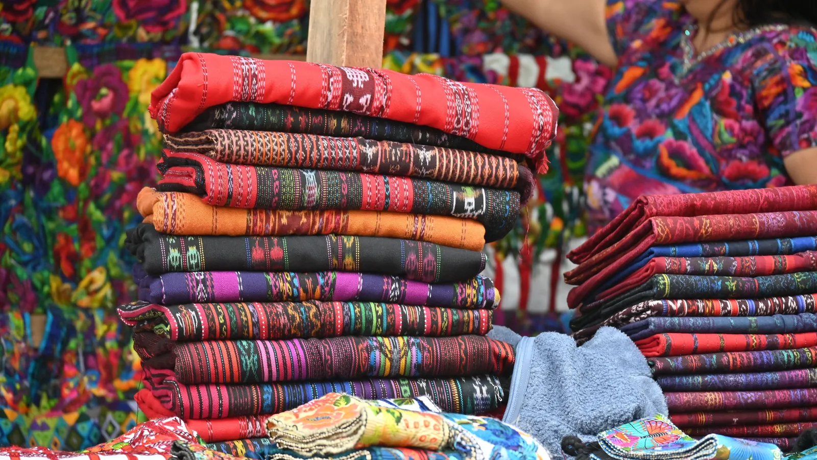 Handwoven textiles stacked at a market in Guatemala