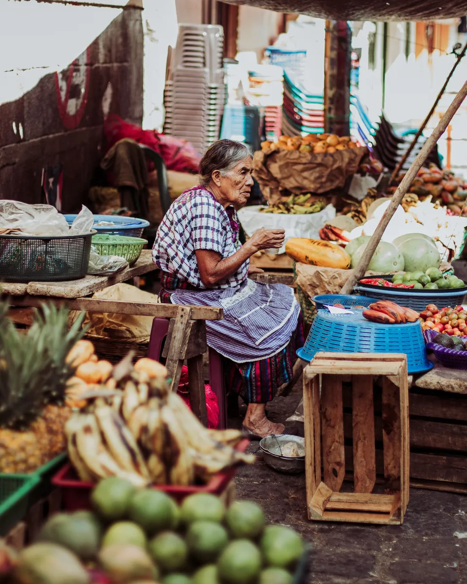 Una vendedora de mercado entre sus frutas y verduras
