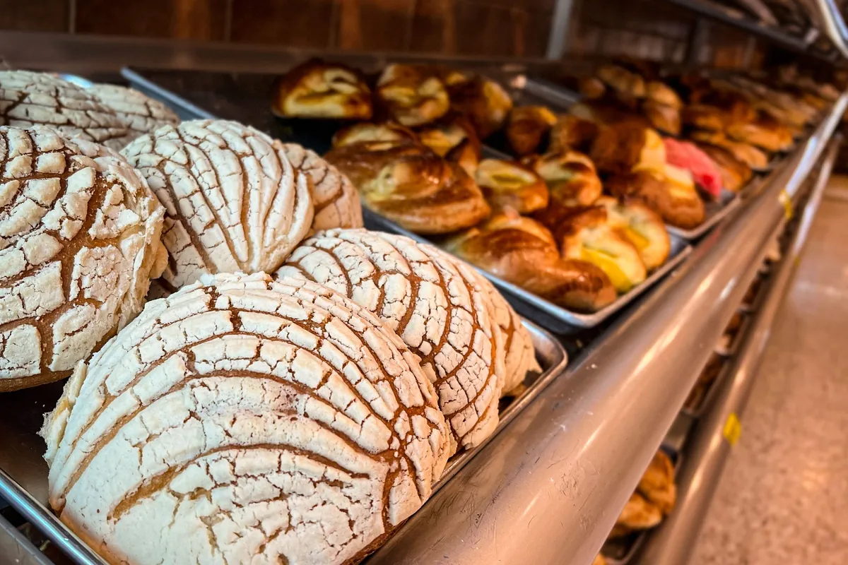 Bandejas de conchas y otro pan dulce en los estantes de una panadería